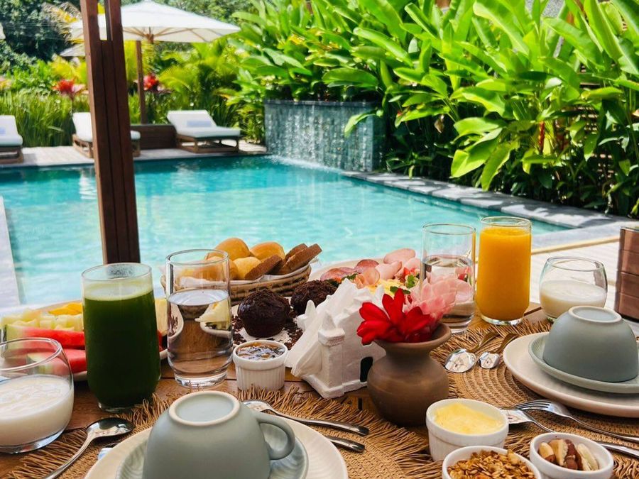 Mesa de café da manhã servida ao lado da piscina.